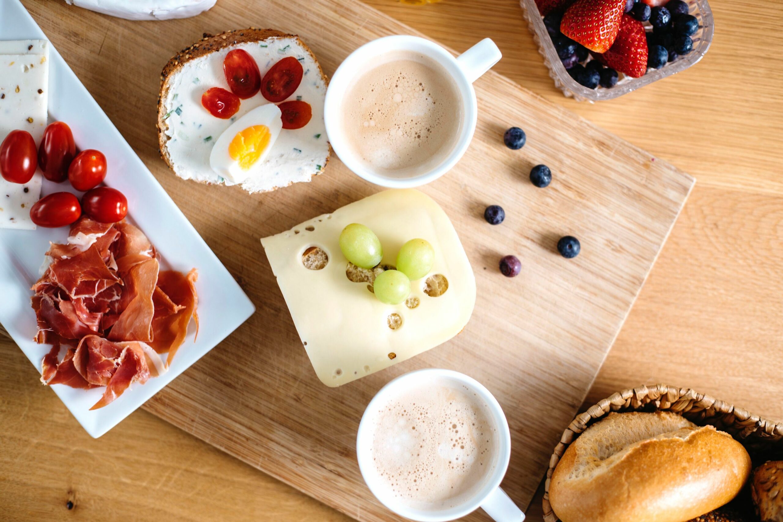 Frühstückstisch von oben: leckere belegte Brote und Brötchen mit Obst und Gemüse