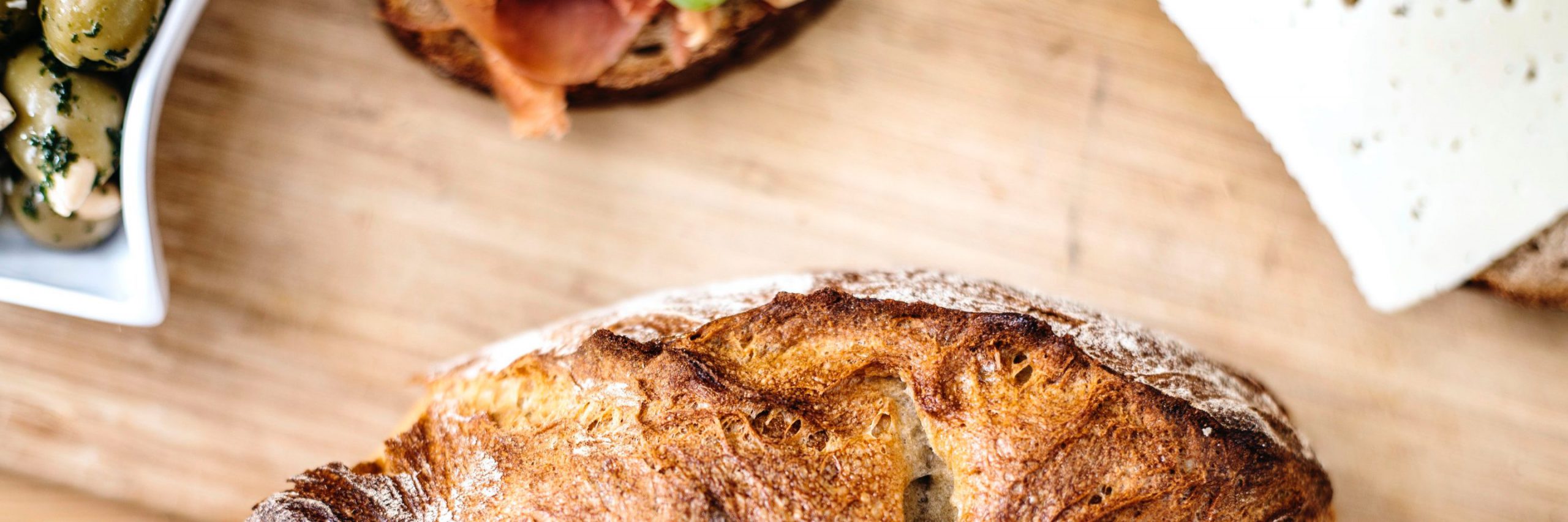 Foto-Fokus auf die tolle Brotkruste. Im Hintergrund zu sehen ist Käse und Tapas.